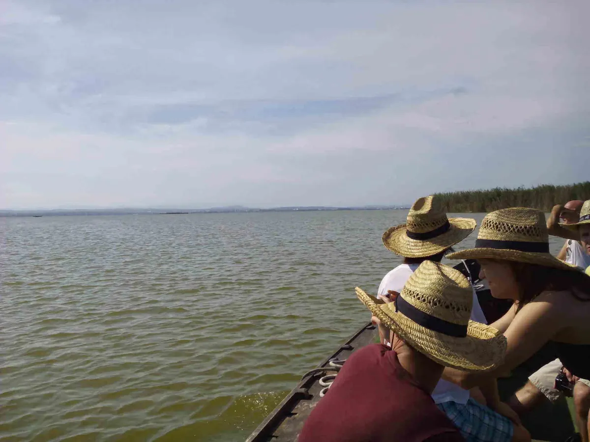 Visitantes con sombrero de paja en una barca tradicional sobre el lago de la Albufera