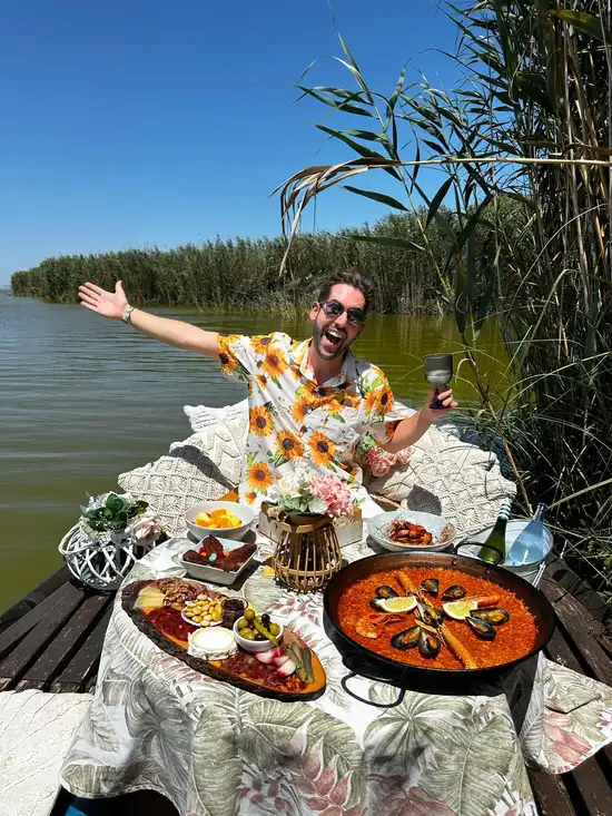 Hombre celebrando con paella valenciana servida en barca en la Albufera de El Palmar