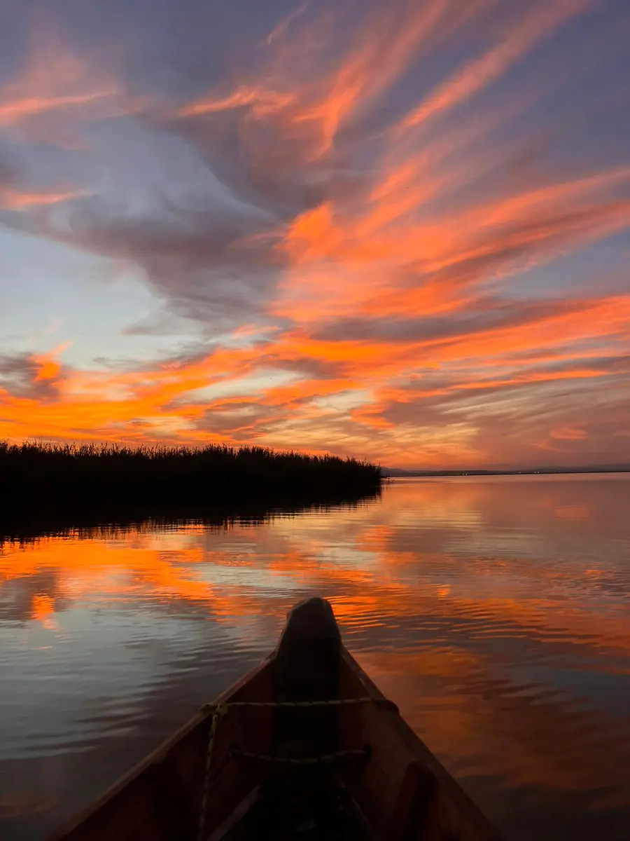 Vista desde la proa de barca tradicional hacia espectacular atardecer en la Albufera