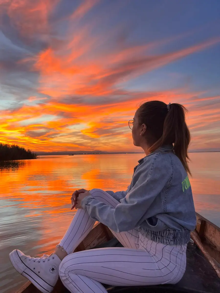 Turista en barca contemplando la puesta de sol sobre el lago de la Albufera