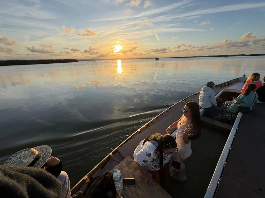 Turistas disfrutando del atardecer desde una barca en el lago de la Albufera de Valencia