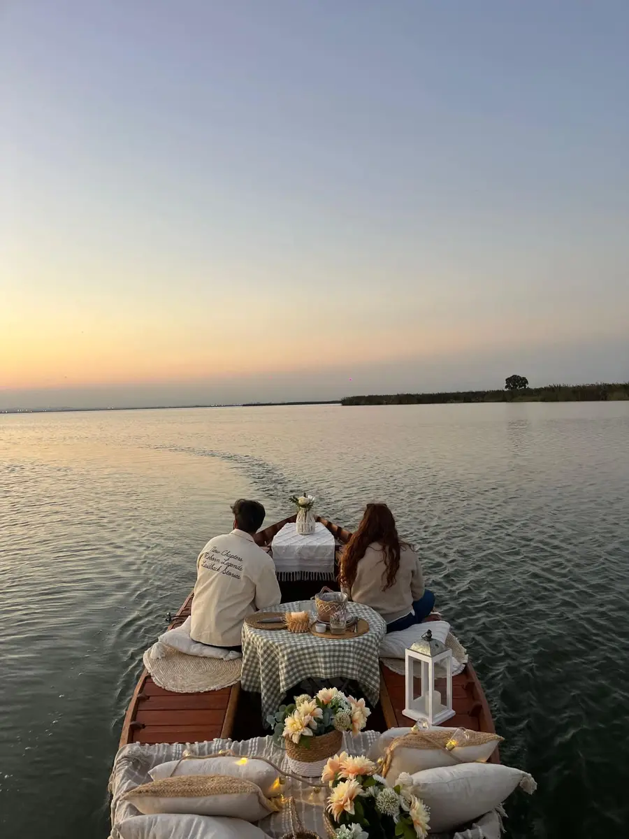 Pareja en barca decorada durante puesta de sol romántica en la Albufera de Valencia