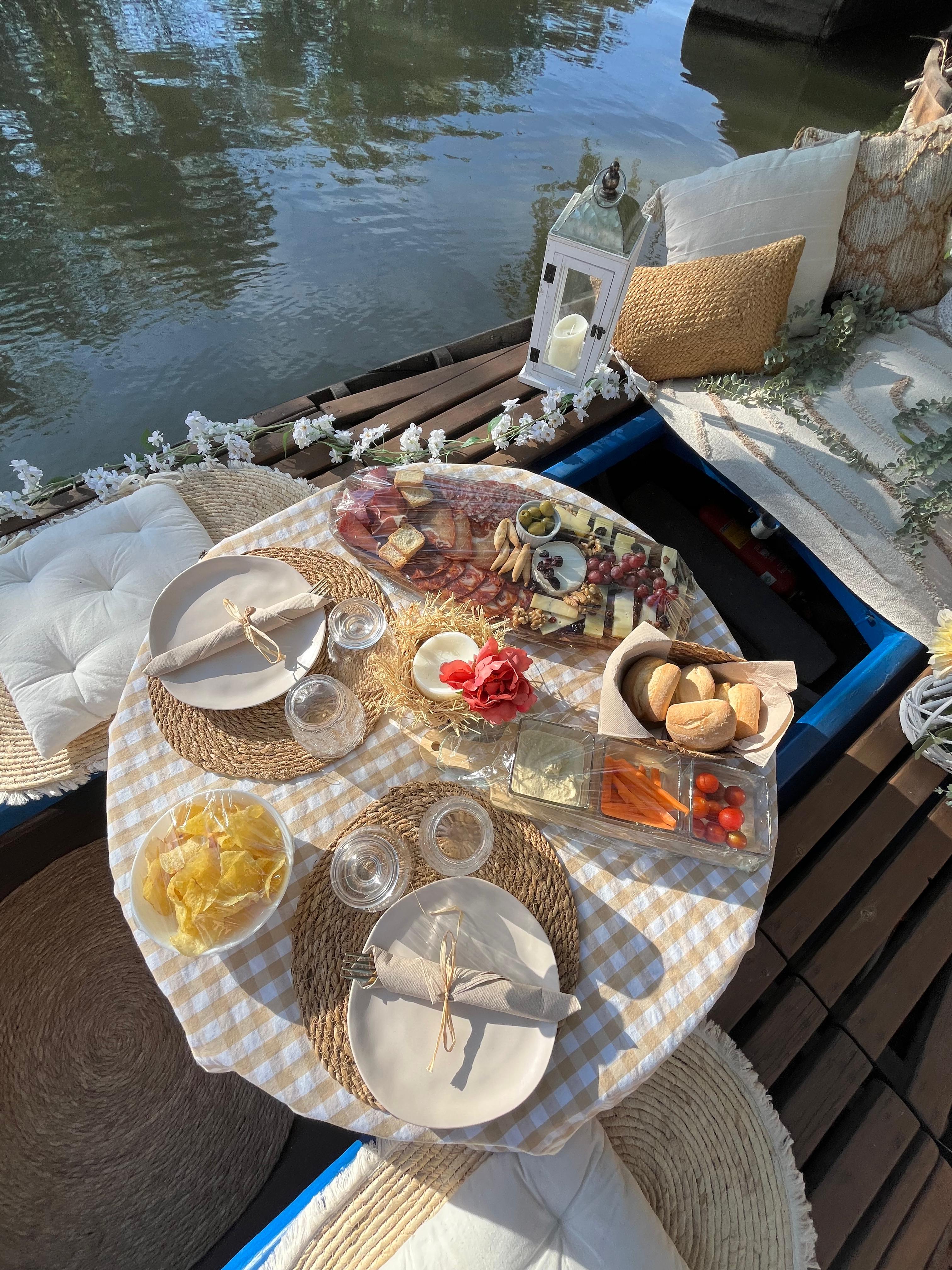 Mesa romántica decorada en barca con vino y aperitivos al atardecer en la Albufera
