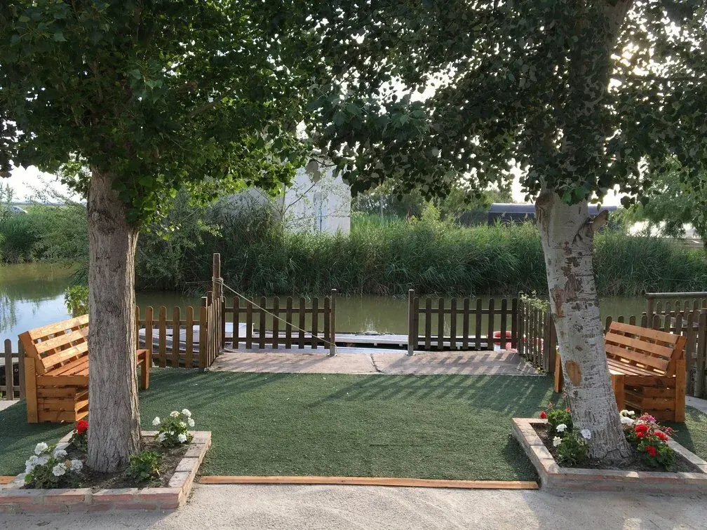Zona de embarque con bancos y árboles junto al canal de El Palmar